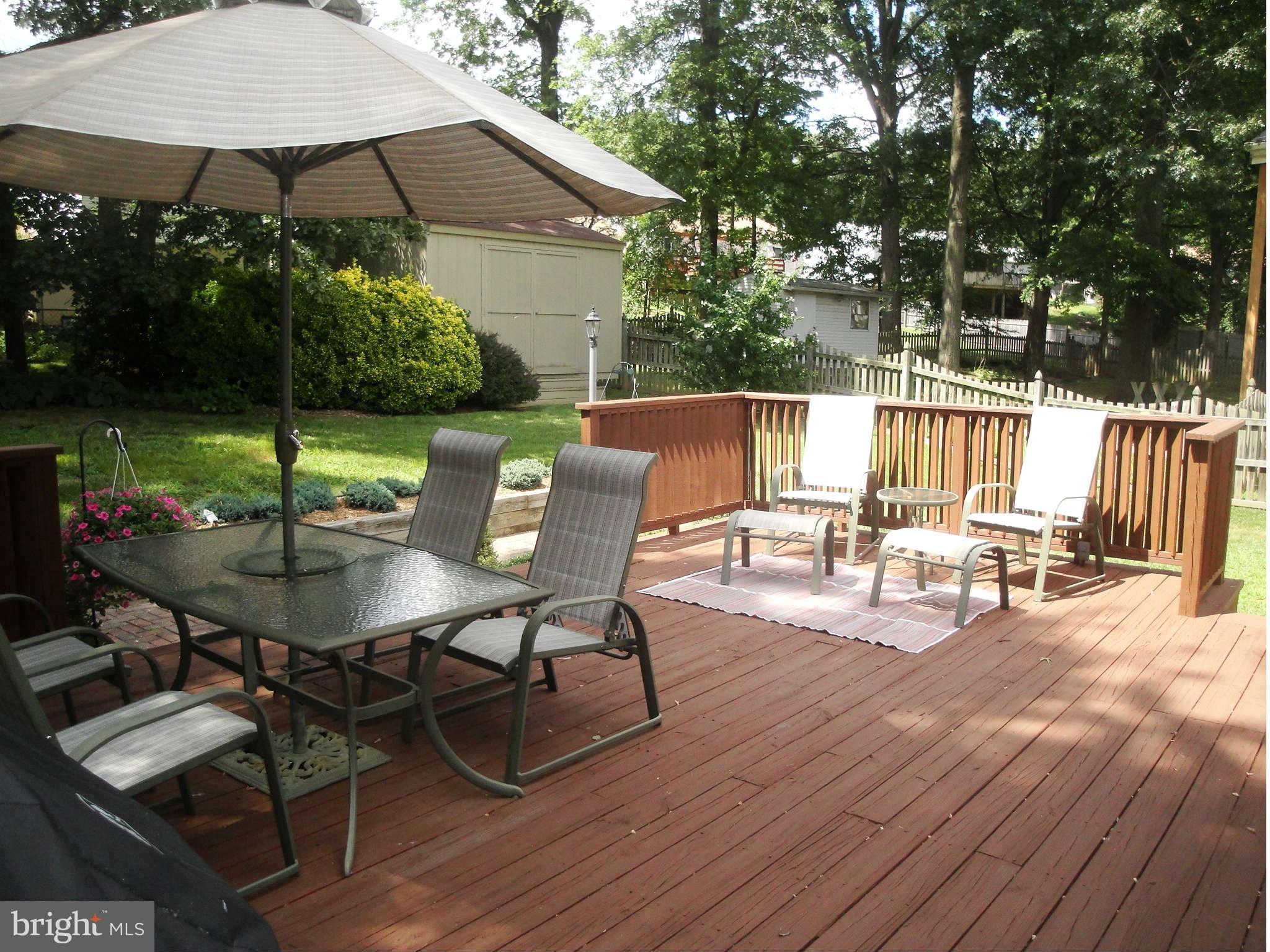 6406 Darwin Road Laurel, MD 20707 - Photo 16 of 22 a view of a patio with table and chairs under an umbrella with wooden floor and fence