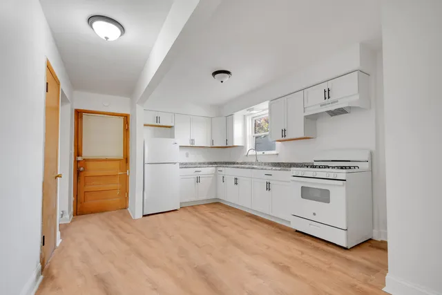 a kitchen with stainless steel appliances white cabinets and wooden floors