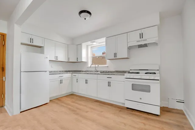 a kitchen with stainless steel appliances granite countertop a refrigerator sink and white cabinets