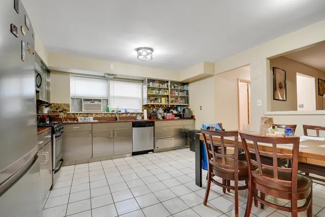 a kitchen with stainless steel appliances a table and chairs in it