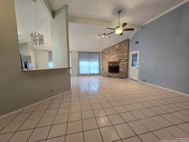 a view of an empty room with a fireplace and a chandelier fan