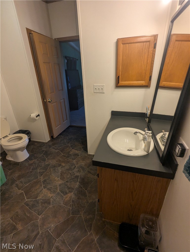 17960 Raven Road Salesville, OH 43778 - Photo 20 of 27 Bathroom featuring a vanity with a white basin sink, chrome faucet, wood-finish cabinetry, and a dark countertop