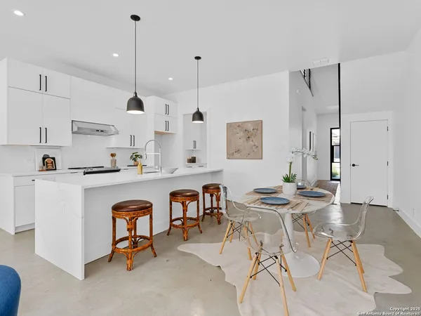 a kitchen with stainless steel appliances kitchen island granite countertop a table chairs and white cabinets