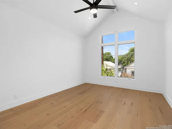 an empty room with windows and ceiling fan