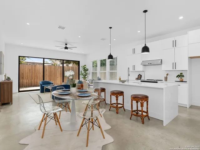 a kitchen with stainless steel appliances kitchen island granite countertop a stove a sink a dining table and chairs with wooden floor