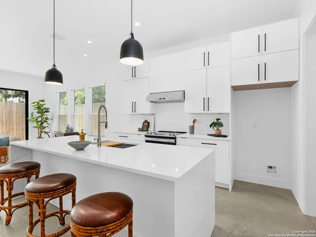 a kitchen with a sink a stove and chairs