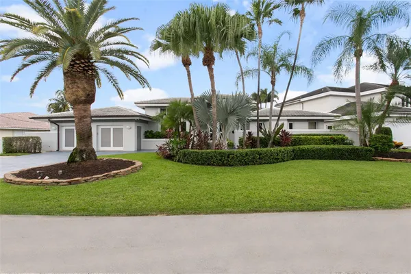 a front view of a house with a garden and palm trees