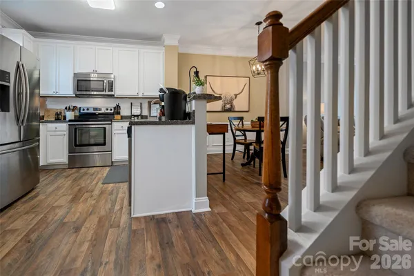 a kitchen with granite countertop a refrigerator stove and wooden floor