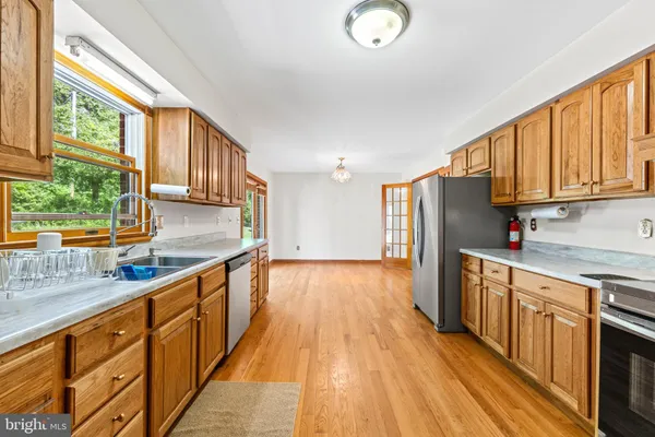 a kitchen with stainless steel appliances granite countertop a stove a sink dishwasher and a refrigerator with wooden floor
