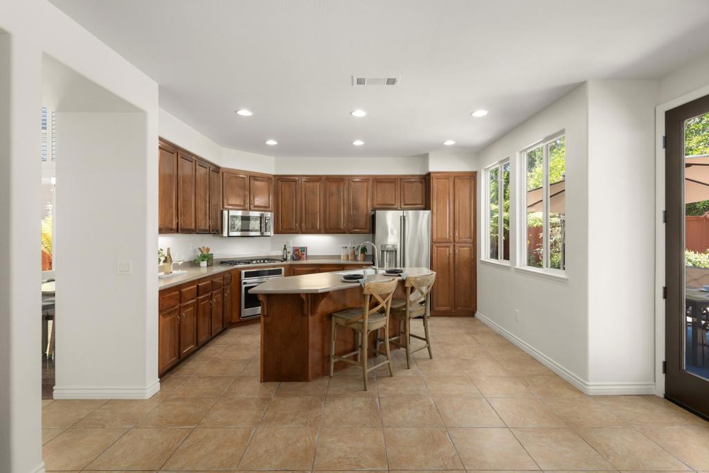 5439 Foxtail Loop Carlsbad, CA 92010 - Photo 13 of 47 a kitchen with stainless steel appliances kitchen island granite countertop a table chairs sink and cabinets