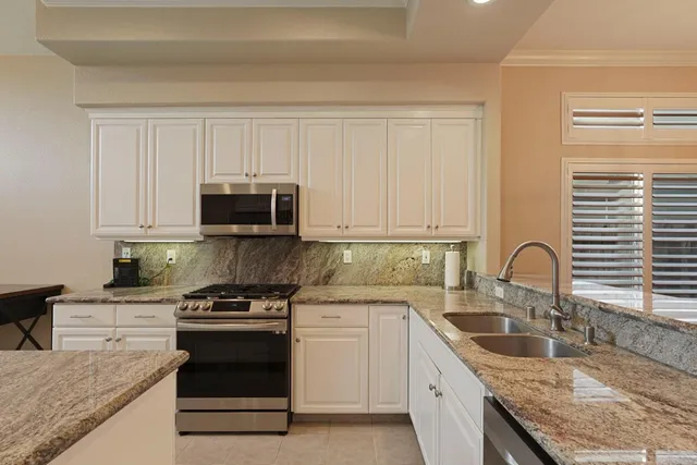 a kitchen with granite countertop a sink stainless steel appliances and cabinets