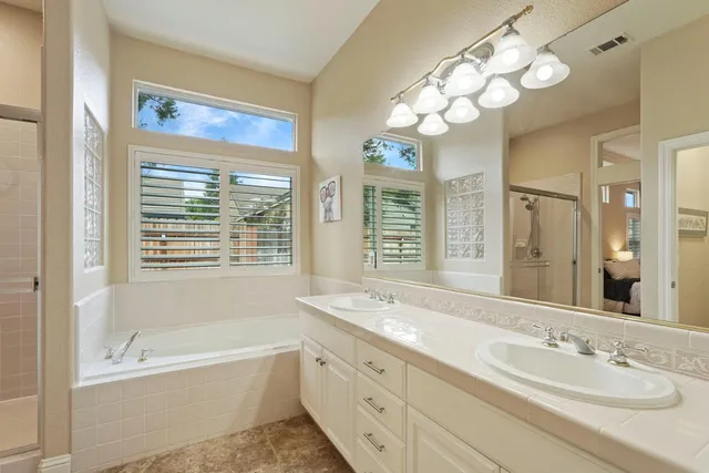 a bathroom with a tub a double vanity sink and a mirror