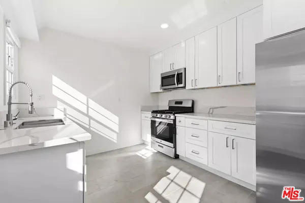 a kitchen with granite countertop a sink a stove and cabinets