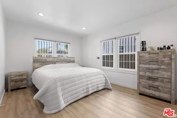 a bedroom with a bed and dresser with wooden floor