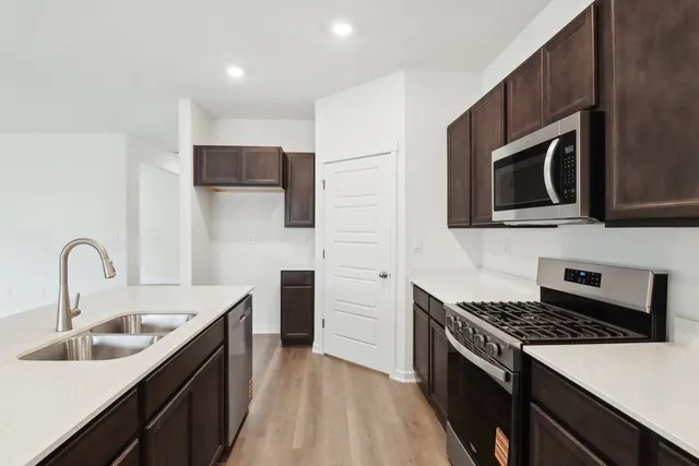 a view of kitchen with microwave a stove and wooden floor