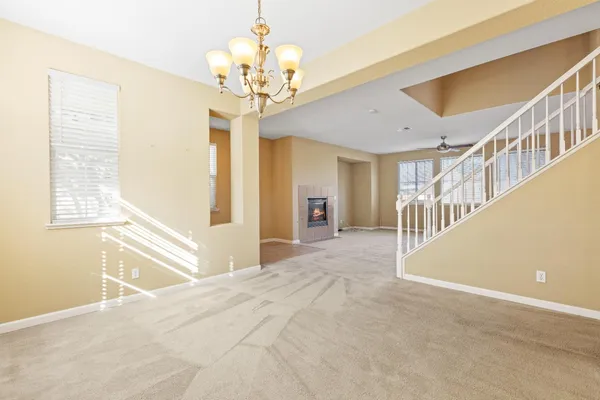 a view of an empty room with wooden floor and a chandelier