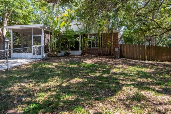 a view of a backyard with large trees and wooden fence