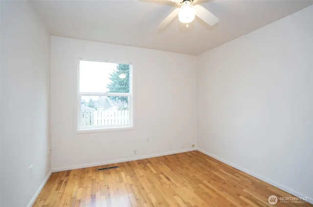 an empty room with a chandelier fan and windows