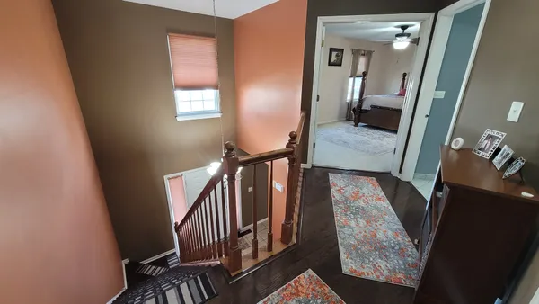a view of a hallway with wooden floor and staircase
