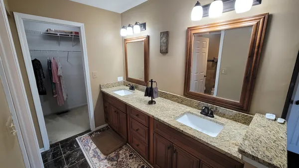 a bathroom with a granite countertop double vanity sink and a mirror