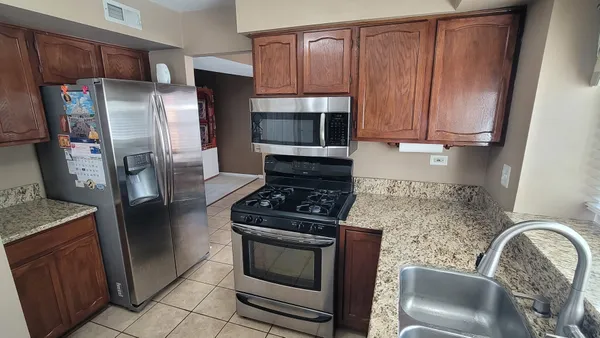 a kitchen with granite countertop a refrigerator stove and microwave