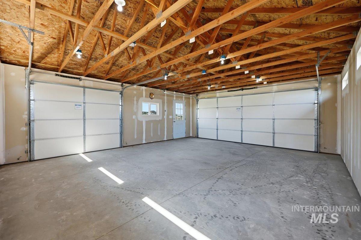 13496 Hockberger Ranch Road Caldwell, ID 83607 - Photo 32 of 40 Spacious two-car garage featuring a concrete floor and exposed wood ceiling trusses