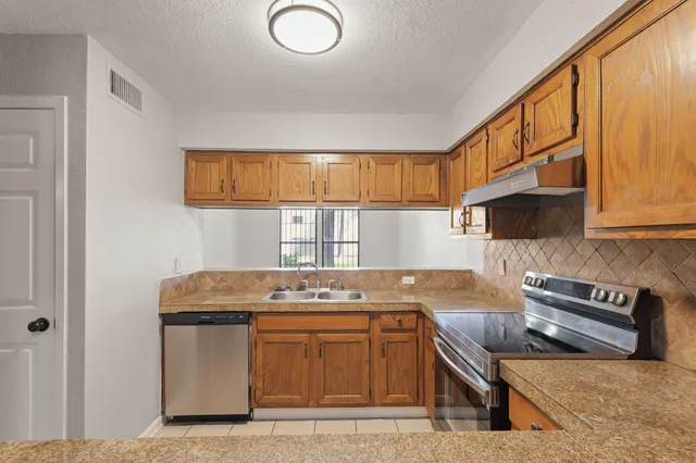 a kitchen with stainless steel appliances granite countertop a stove a sink and a microwave