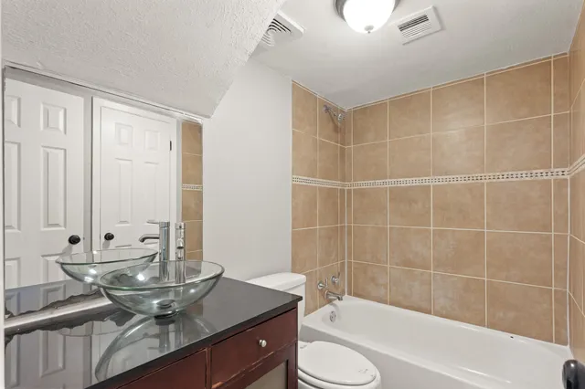 a bathroom with a granite countertop sink a toilet and bathtub