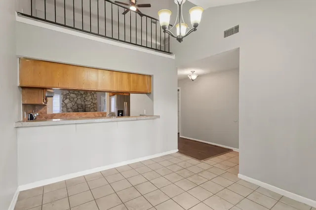 a view of an empty room with window and chandelier fan