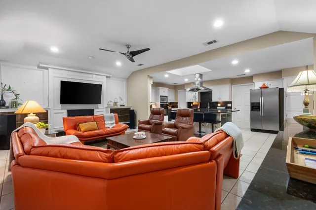 a living room with furniture kitchen and a flat screen tv