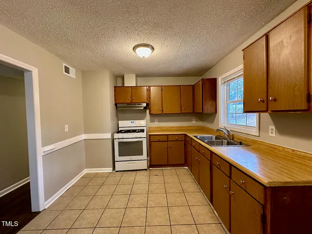 a kitchen with a sink a stove top oven and cabinets