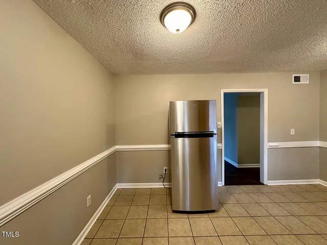 a view of a refrigerator in kitchen and empty room