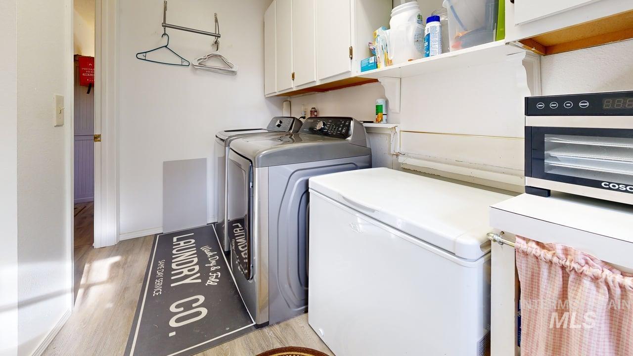 1322 Grelle Avenue Lewiston, ID 83501 - Photo 21 of 22 Laundry room featuring light wood-type flooring, washer and clothes dryer, and cabinet space