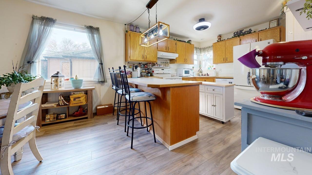 1322 Grelle Avenue Lewiston, ID 83501 - Photo 6 of 22 Two tone kitchen with light countertops, white appliances, a breakfast bar area, a peninsula, and light wood-style floors
