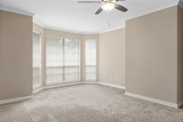 an empty room with chandelier fan and windows