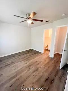 an empty room with wooden floor fan and windows