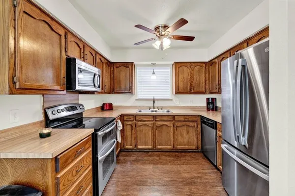 a kitchen with stainless steel appliances granite countertop a stove top oven a sink dishwasher a refrigerator and cabinets with wooden floor