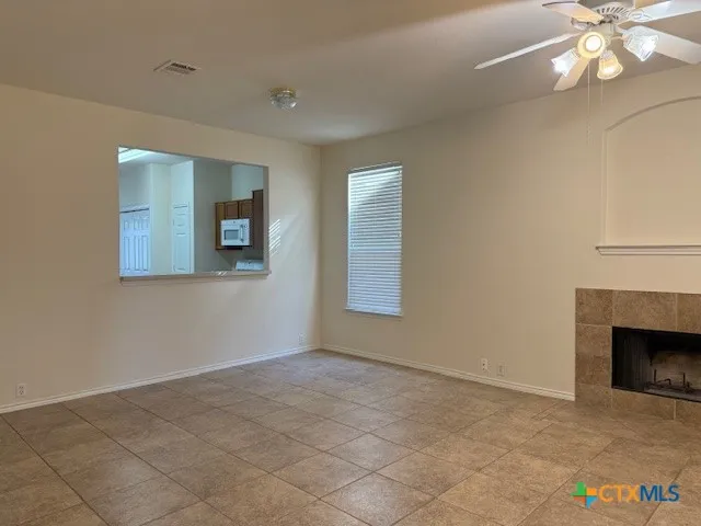 a view of an empty room with window and chandelier fan
