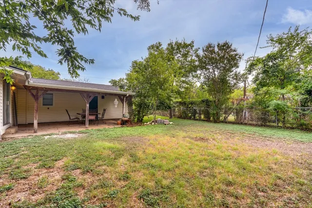 a view of a house with backyard and trees