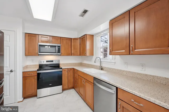 a kitchen with stainless steel appliances granite countertop a sink stove microwave and refrigerator