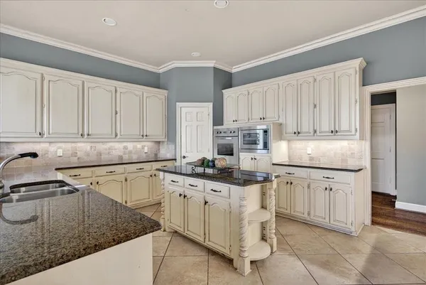 a kitchen with granite countertop a sink stove and cabinets