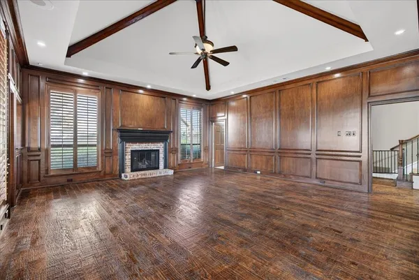 a view of an empty room with wooden floor fireplace and a window