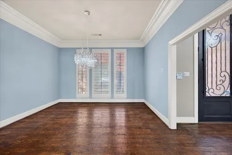 an empty room with wooden floor and chandelier