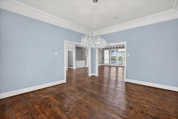 an empty room with wooden floor and chandelier