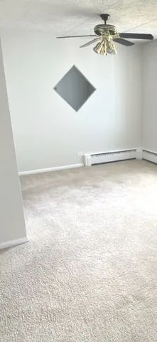 an empty room with a ceiling fan and carpet