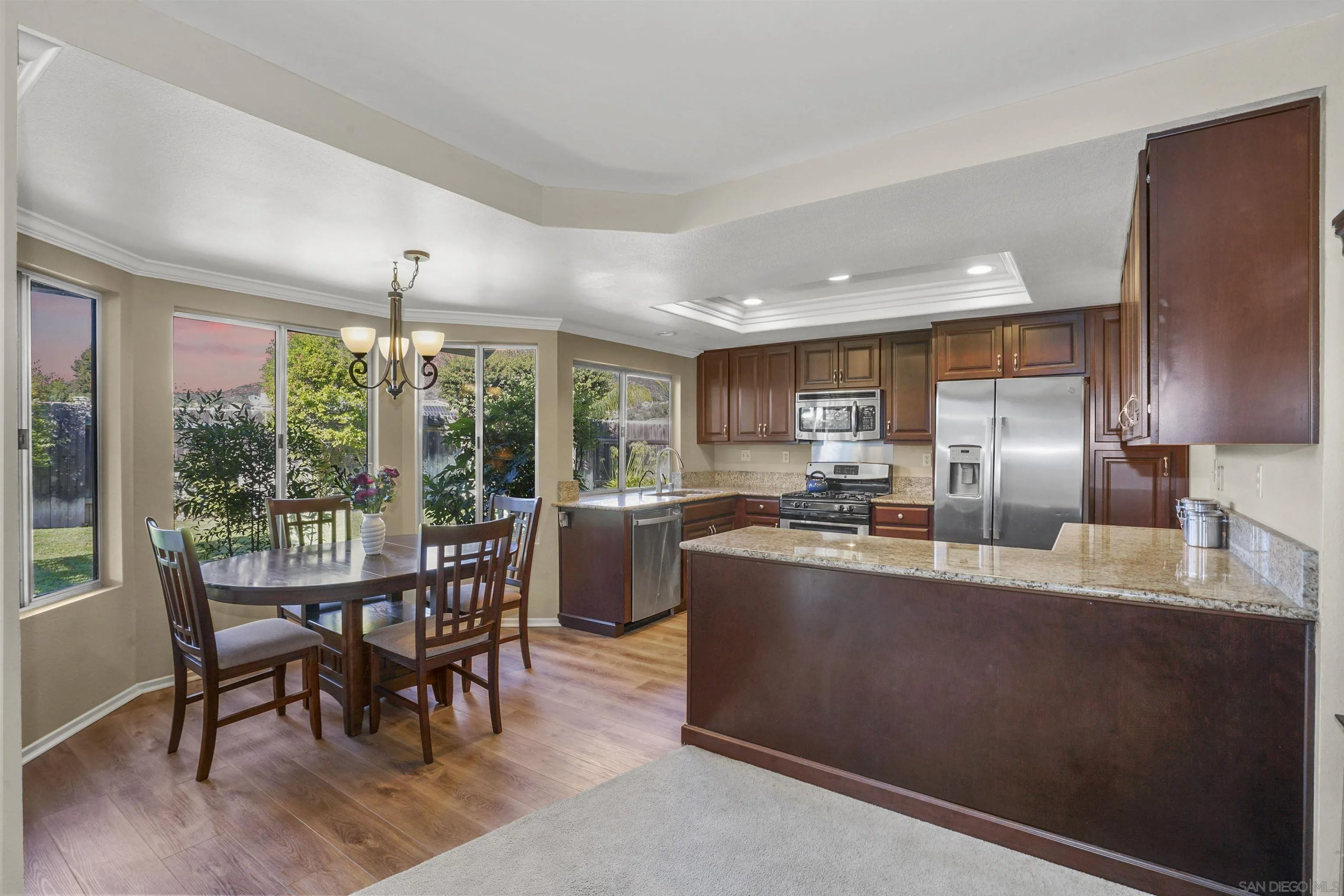 2119 Packard Place El Cajon, CA 92019 - Photo 6 of 29 a kitchen with stainless steel appliances granite countertop a stove top oven a sink dishwasher a dining table and chairs with wooden floor