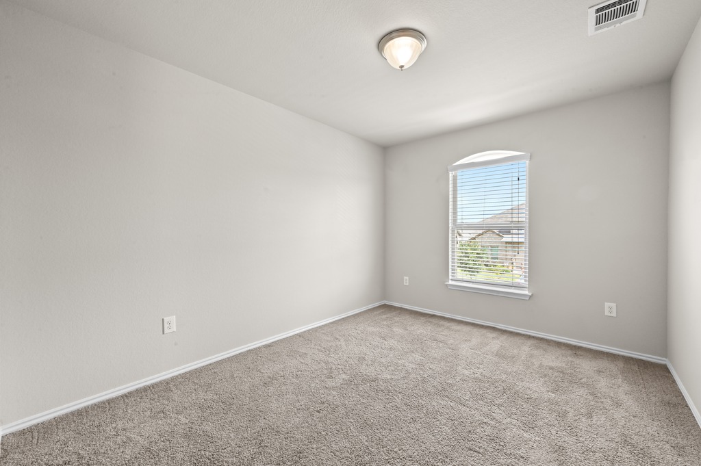 209 Noddy Road Buda, TX 78610 - Photo 22 of 27 Soft carpeted flooring and neutral walls define this versatile secondary bedroom space.
