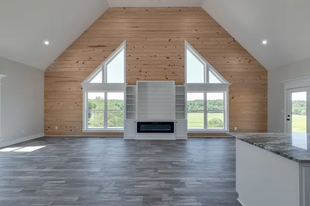 a view of an empty room with wooden floor fireplace and a window