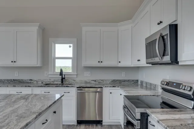 a kitchen with granite countertop a sink stove and cabinets