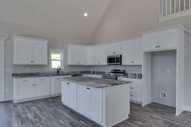 a kitchen with granite countertop white cabinets sink and stainless steel appliances